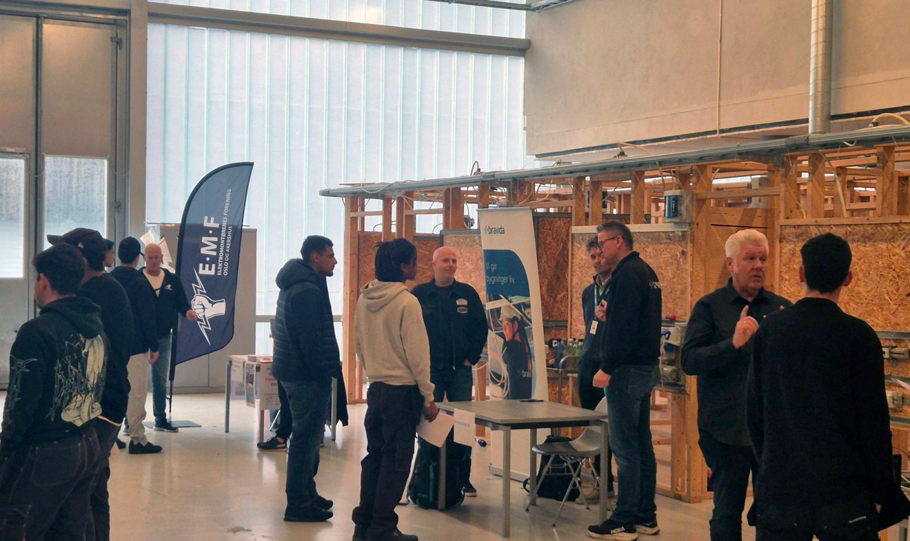 en gruppe mennesker som står i et rom med et bord og en plakat
