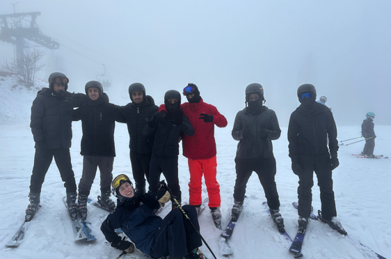 En gruppe mennesker poserer for et bilde på snøski