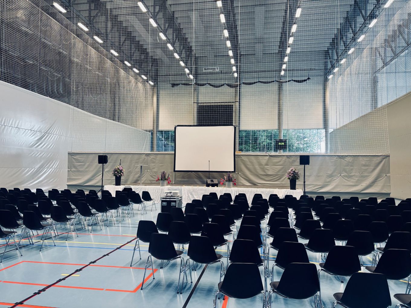 En stor arena med skjerm og folk i den En stor arena med skjerm og folk i den
