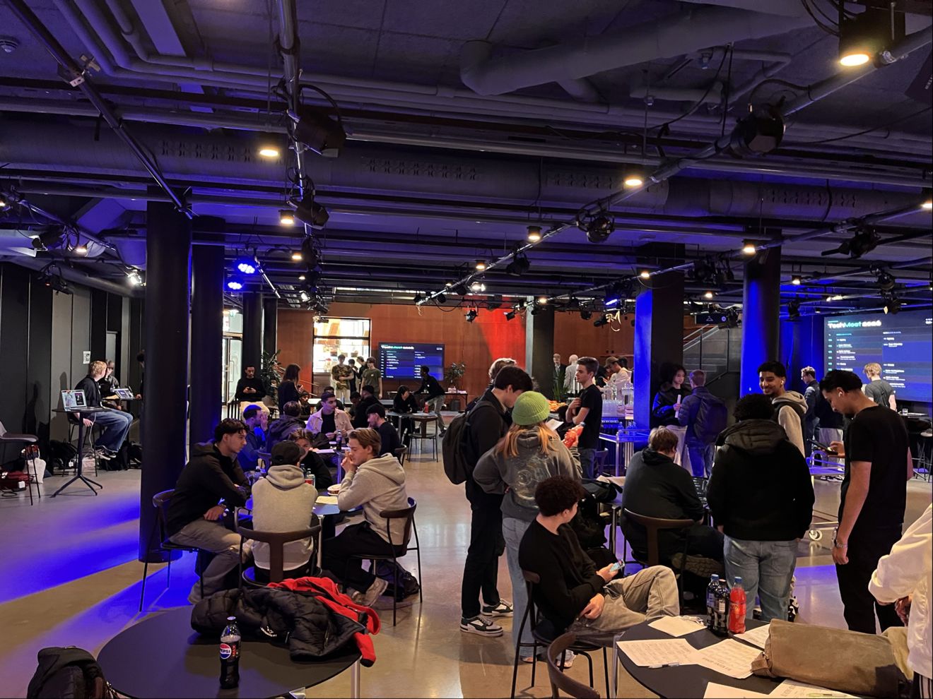 en gruppe mennesker som sitter i et rom med en stor skjerm