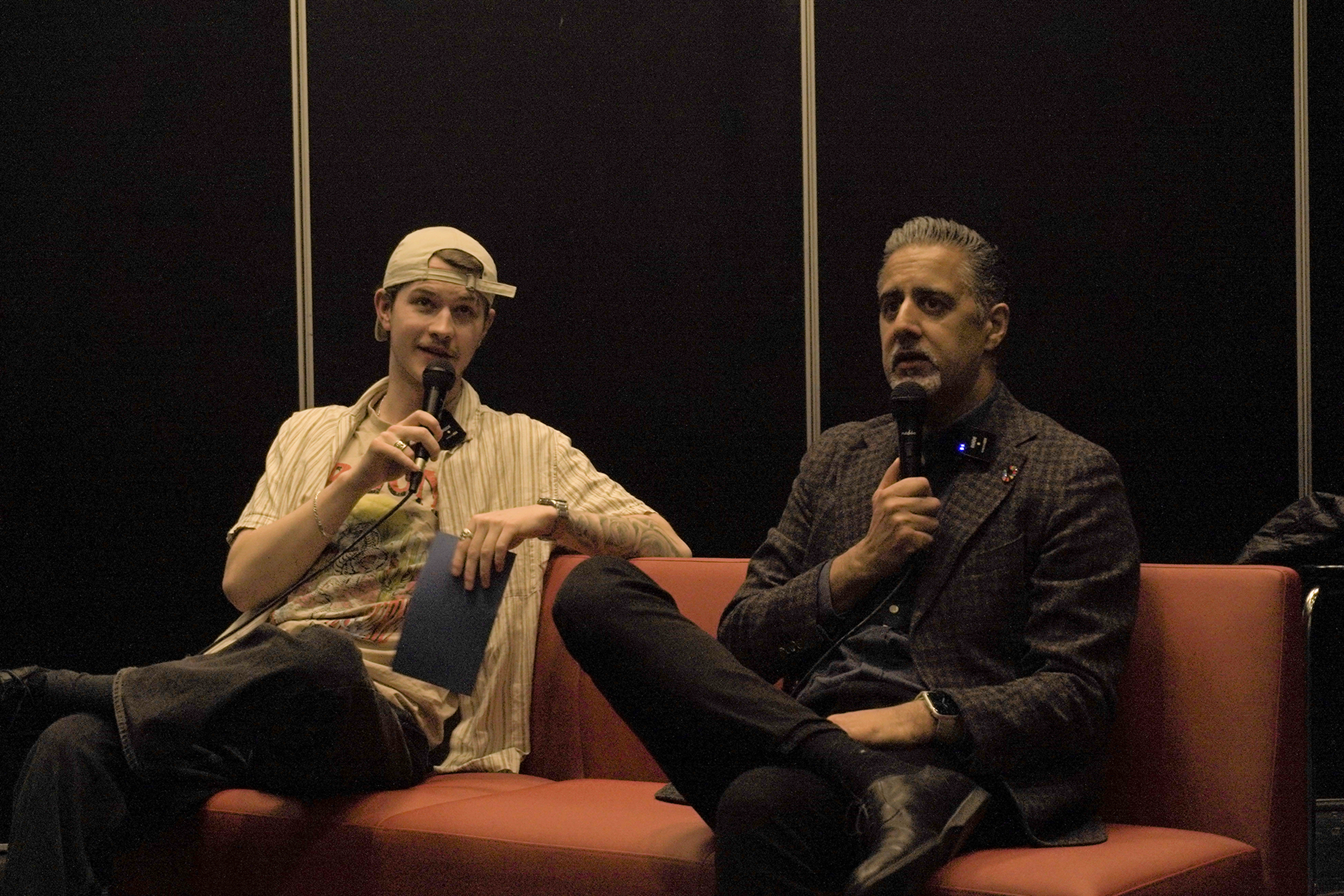 en person som sitter i en sofa med en mikrofon ved siden av en person som sitter på en stol