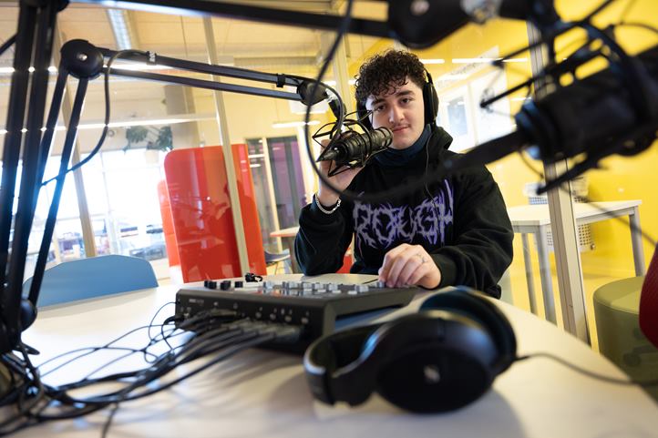 en person som har hodetelefoner og sitter ved et skrivebord med en datamaskin