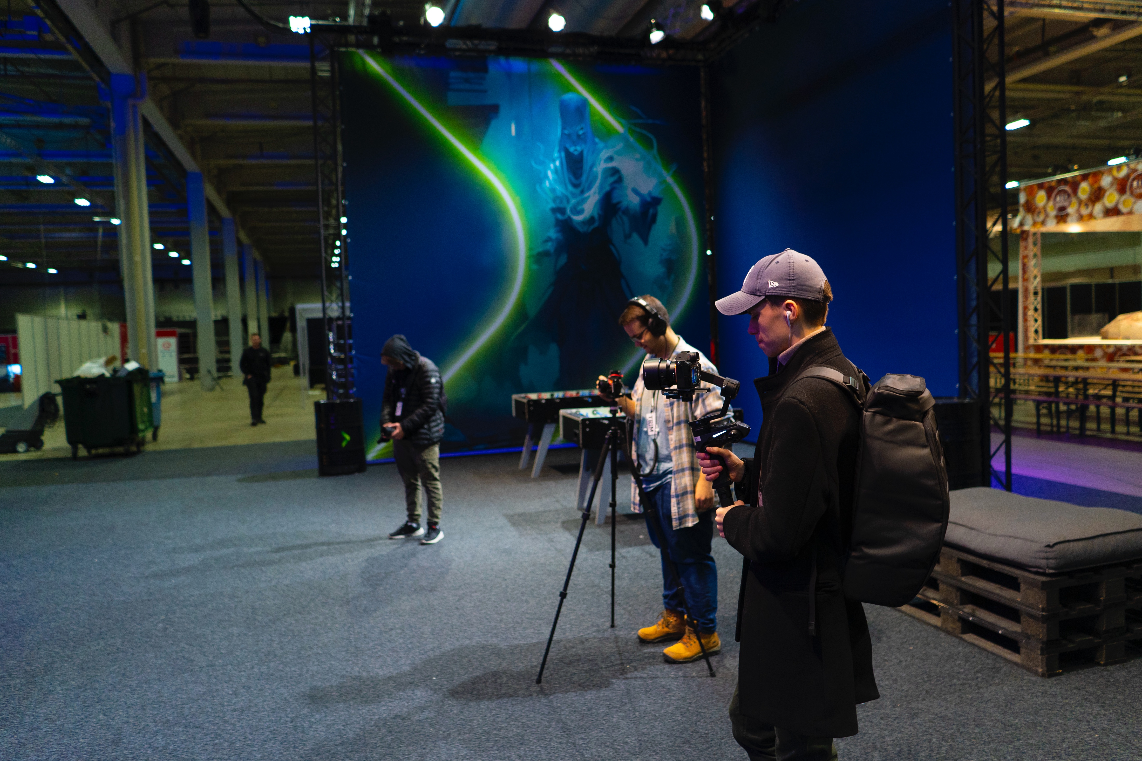 en person som står ved siden av en person med et kamera foran en stor skjerm