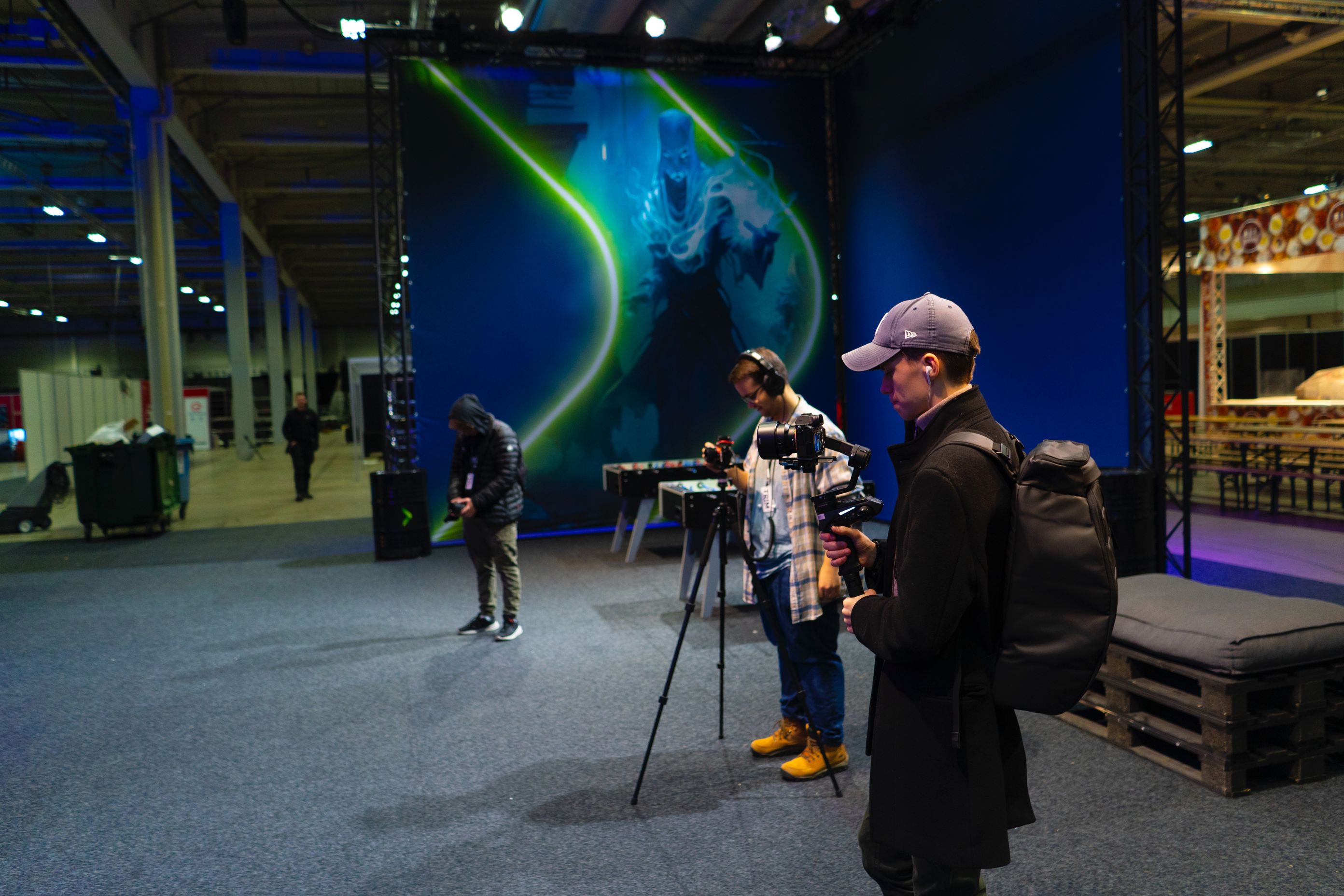 en person som står ved siden av en person med et kamera foran en stor skjerm