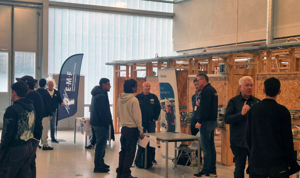 en gruppe mennesker som står i et rom med et bord og en plakat