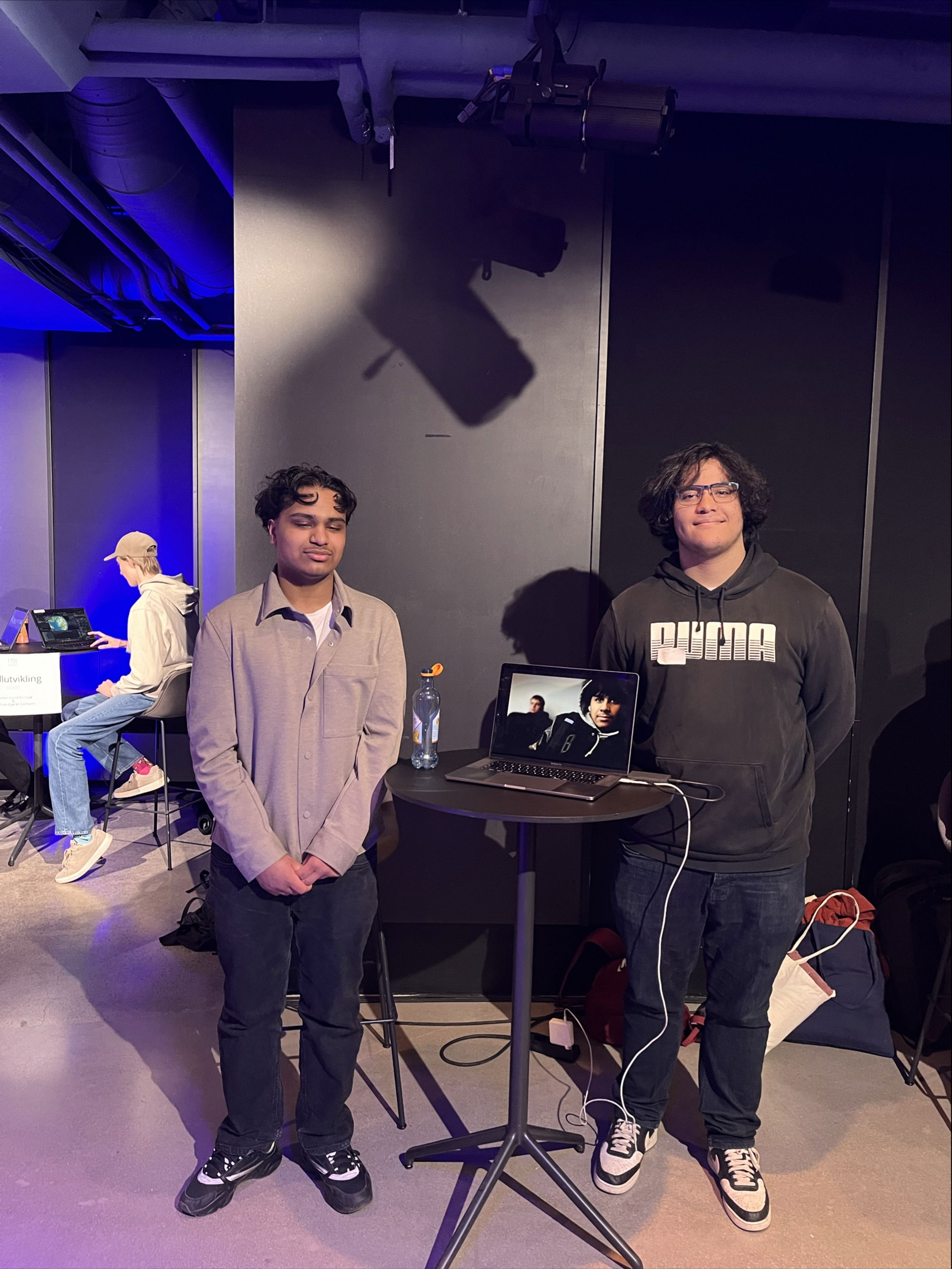 et par menn som sto ved siden av et bord med en laptop på