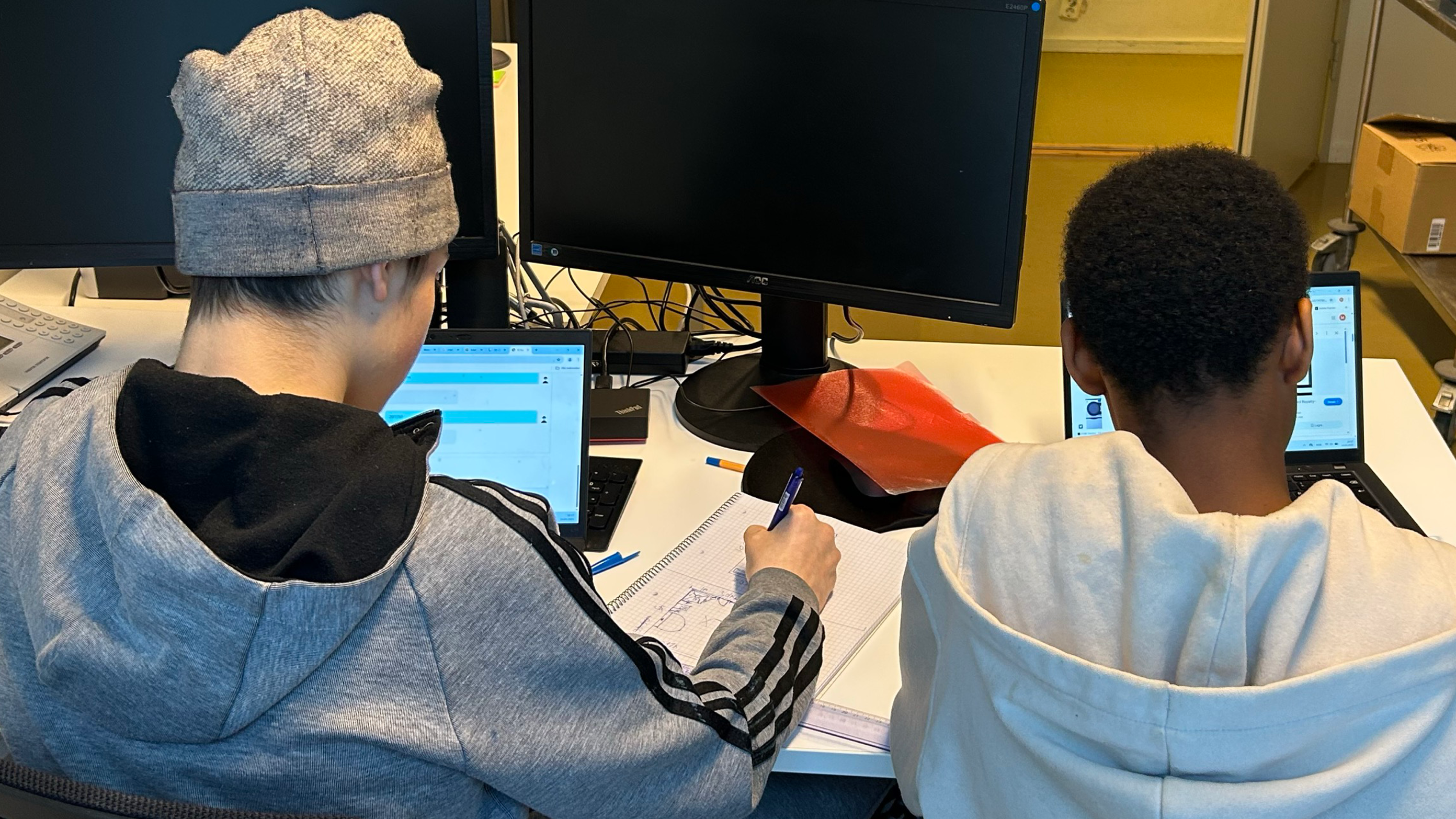 et par menn som sitter ved et skrivebord med datamaskiner